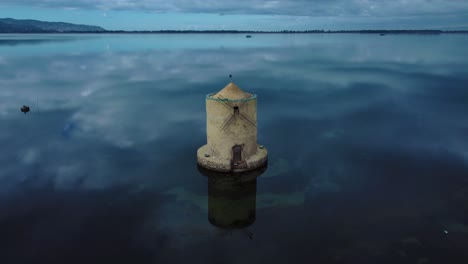 old spanish windmill in the lagoon at old island town orbetello close to monte argentario and the maremma nature park in tuscany, italy, with blue sky and calm blue water