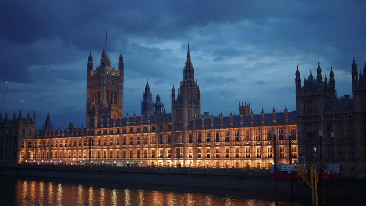 View of the Palace of Westminster at night with its lights reflecting on the River Thames, London, England