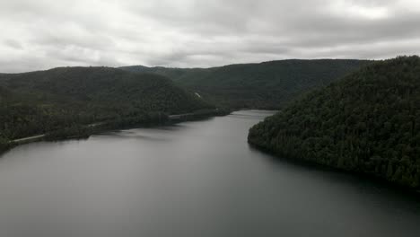 Nubes-Oscuras-Cubriendo-El-Tranquilo-Lago-Y-El-Exuberante-Bosque-En-La-Península-De-Gaspe,-Quebec,-Canadá---Drone-Aéreo