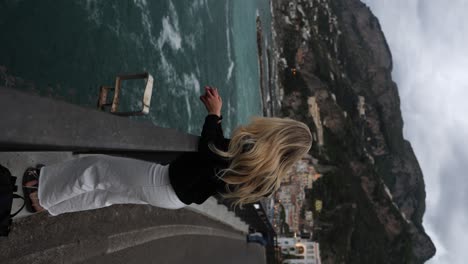 turista rubia admirando la hermosa costa de amalfi en italia, vertical