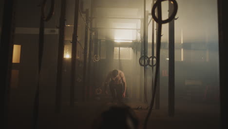 man working out in a gym with ropes and rings