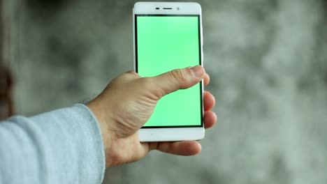 closeup man hand holding and touching phone with green screen vertical