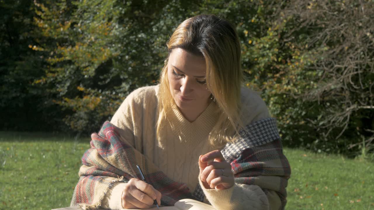 Bella donna che contempla mentre scrive all'aperto