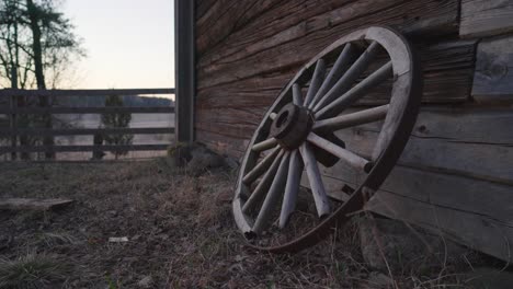 old broken cart wheel leaning against a barn