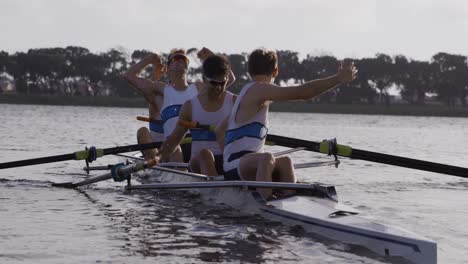 front view of male rower team celebrating on the lake