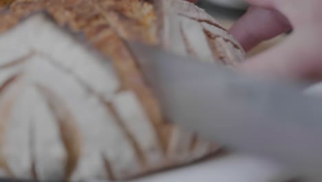 extreme close-up rack focus of a knife cutting through a loaf of artisan bread