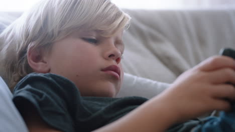 happy-little-boy-using-smartphone-playing-game-relaxing-on-sofa-at-home-child-browsing-online-with-mobile-phone-technology-anti-social-addiction-concept-4k-footage