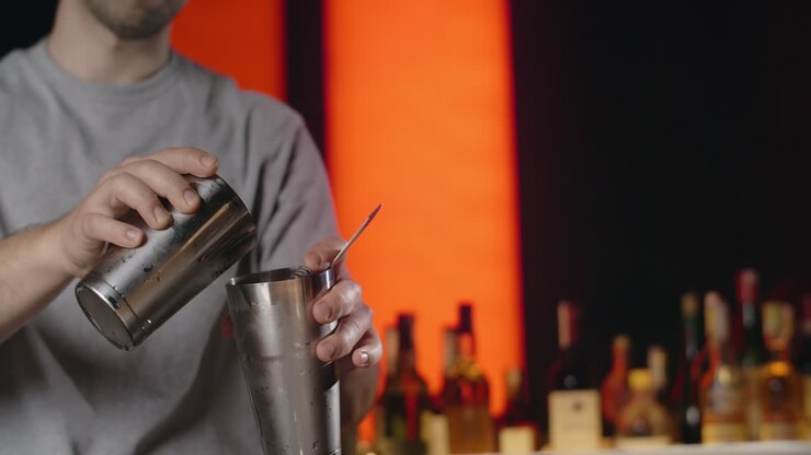 el camarero vertiendo un cóctel rojo.