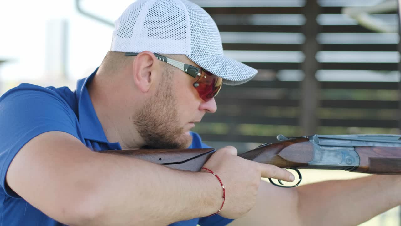 스포츠맨이 이중 배럴 건으로 총을 고, 슈팅 테스트를 위한 스포츠 경기장은 날아다니는 스케이트를 고 있습니다.