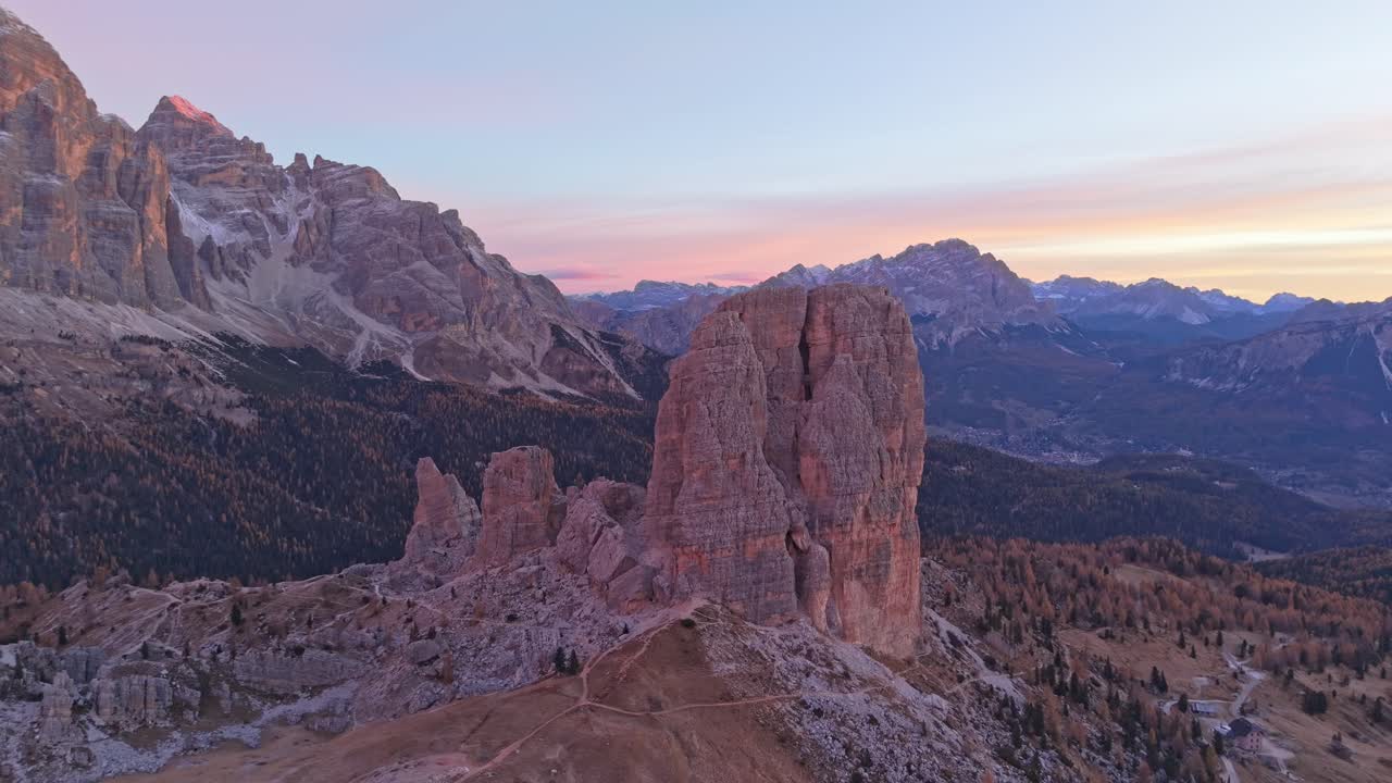 Droneoptagelse af Cinque Torri-toppe, der rager op over alpint terræn i Dolomitterne