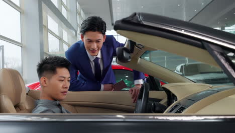 couple with attractive auto dealer in a suit presenting new car model to his client