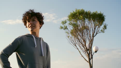 zoom in of attractive young woman in sportswear looking at camera at sunset