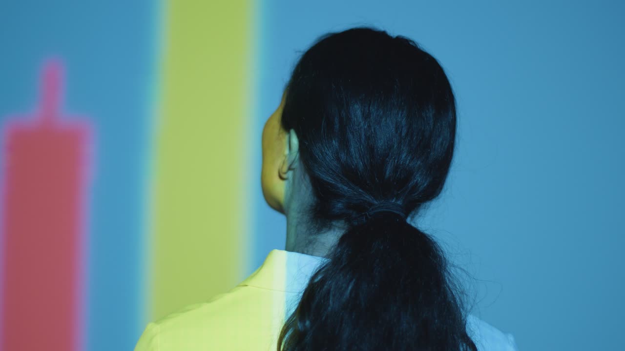 벽 4에 모양과 패턴을 투사하는 몰입 예술 전시회를 방문하는 여성