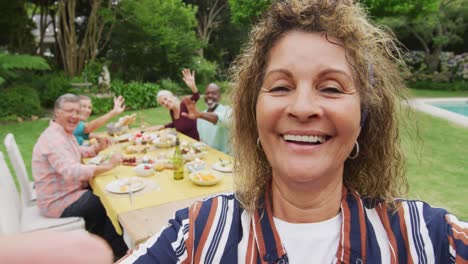 animación de una feliz mujer mayor biracial haciendo una videollamada mientras almuerza con amigos