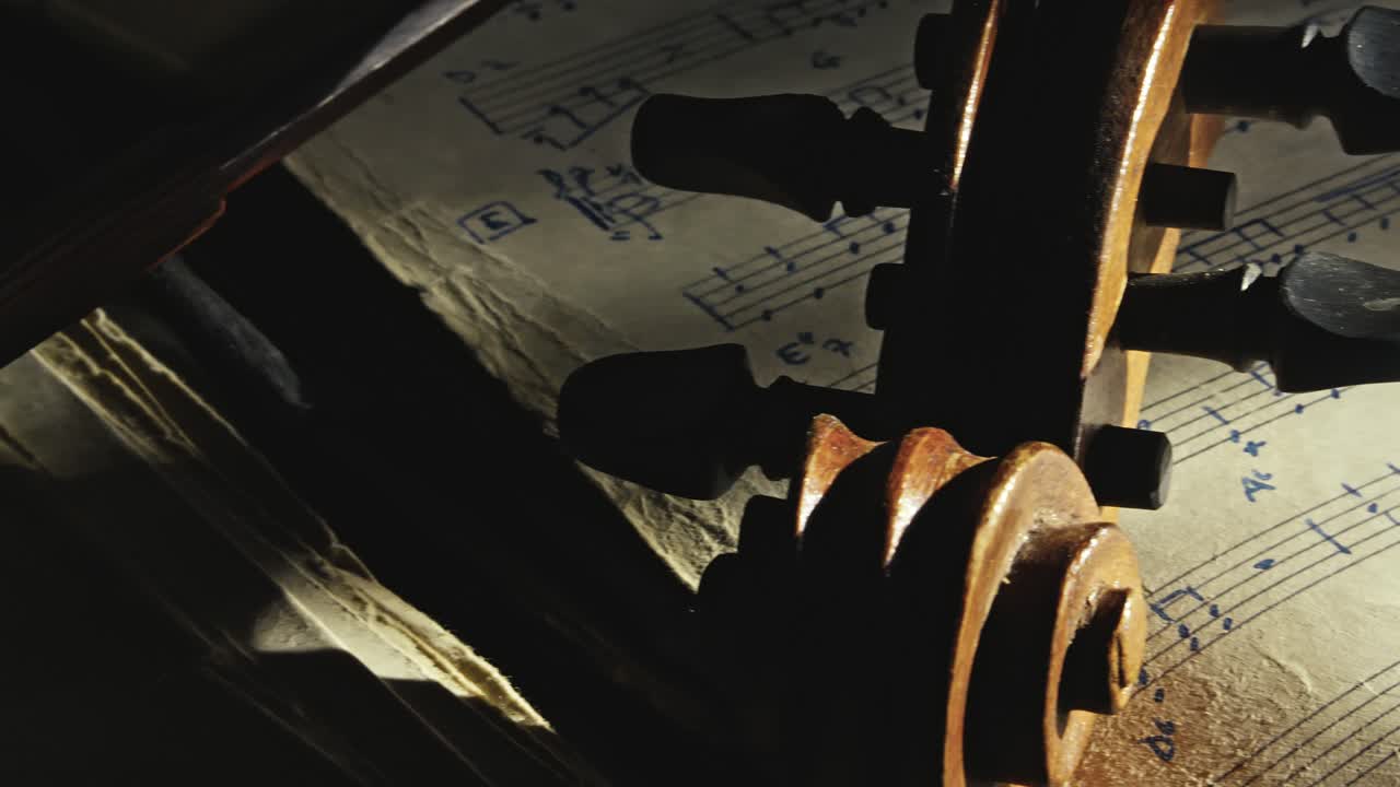 Classical violin lays on aged sheet music in moody revealing close-up