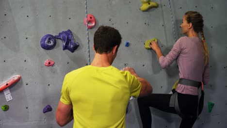 Coach-assisting-a-woman-in-climbing-the-artificial-wall-4k