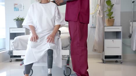 mid section of male doctor talking to caucasian female patient with prosthetic leg at hospital