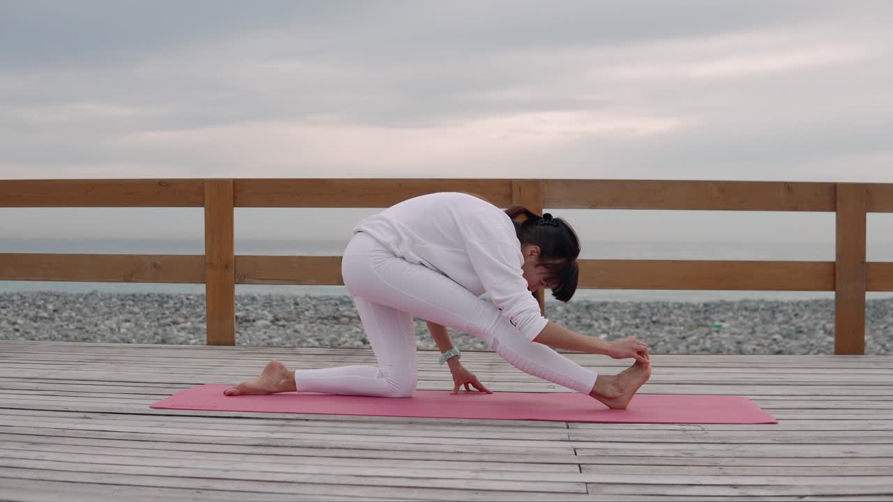 mujer practicando yoga en un paseo marítimo de la playa