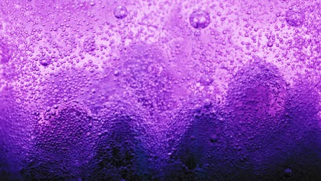 macro shot of big violet bubbles on ground of water and many small bubbles sparkling