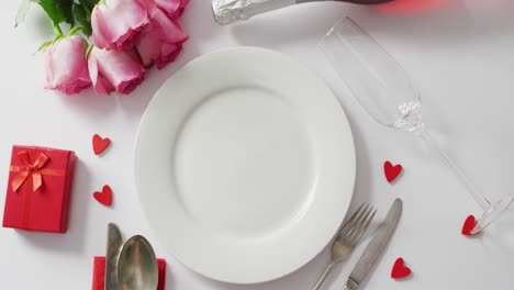 Roses-and-plate-with-cutlery-on-white-background-at-valentine's-day