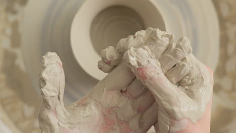 Ceramics artisan cleans his hands of sticky clay after finishing craft work on the throwing wheel