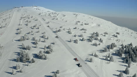 snowcats grooming a ski slope on a snowy mountain