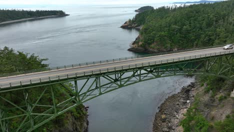 drone perspective of a single car driving across deception pass in washington state