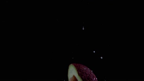 Avocado-Falling-into-Water-Super-Slowmotion,-Black-Background,-lots-of-Air-Bubbles,-4k240fps