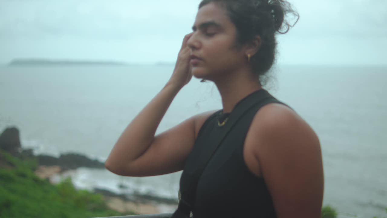 Woman gazes at a cloudy sea. Reflective mood on a calm beach day