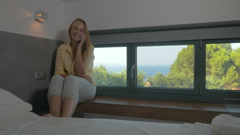 Young-excited-woman-talking-on-mobile-in-hotel