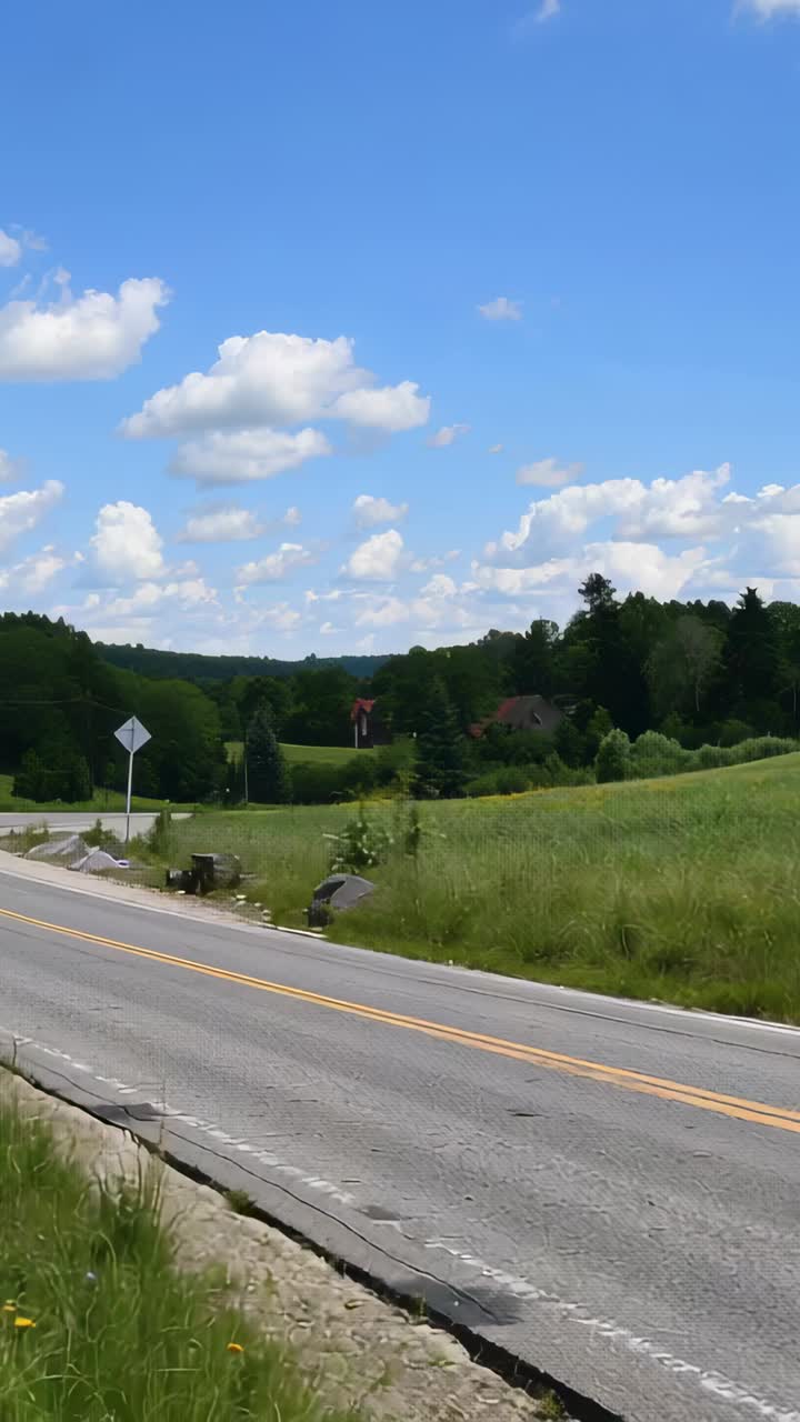 Vertical video: Moving camera reacting to handheld shifting, capturing rural road, sign, red roof