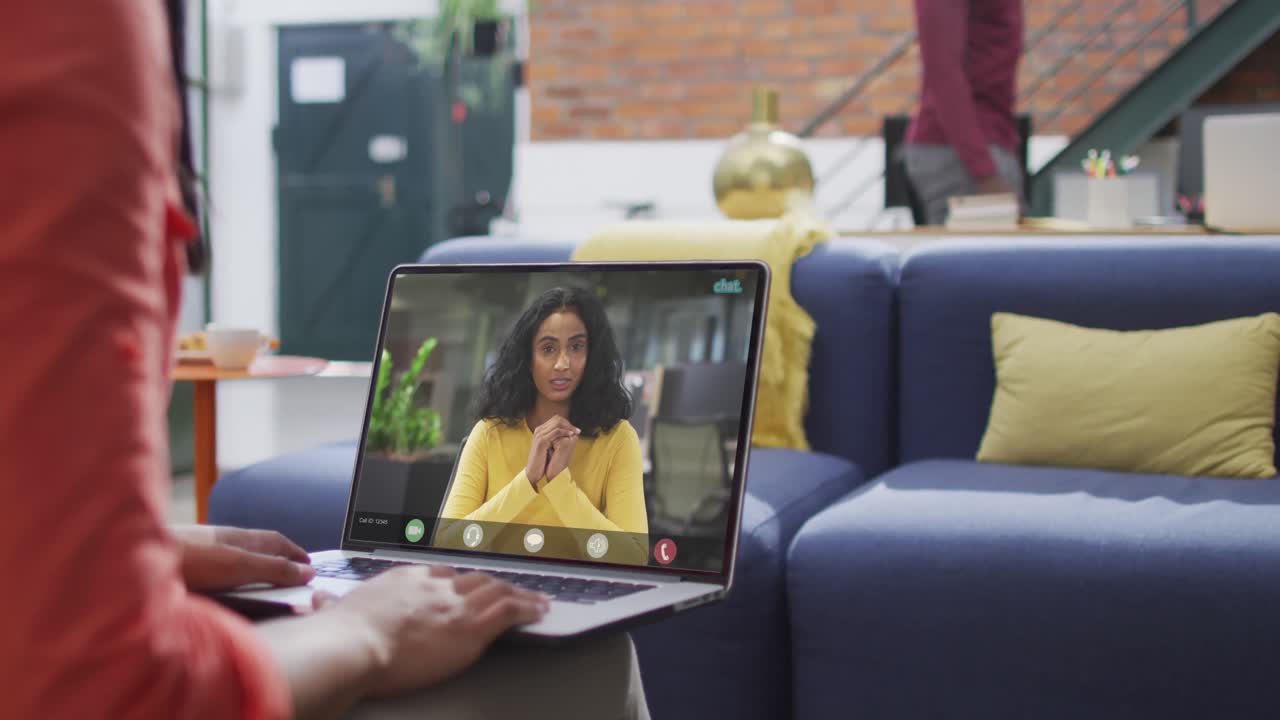 Biracial businesswoman using laptop for video call with biracial business colleague