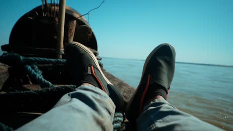 un par de zapatos disparados en la proa de un barco en cámara lenta moviéndose hacia adelante en un río