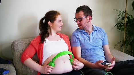 pregnant woman placing headphones while interacting with man