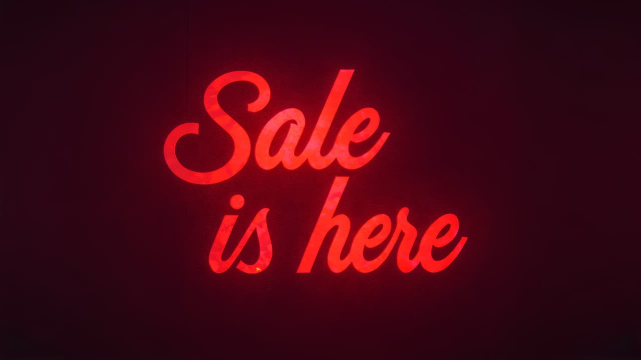 Tracing moving spark lighting neon-style sign reading Sale here at studio wall, promoting sale