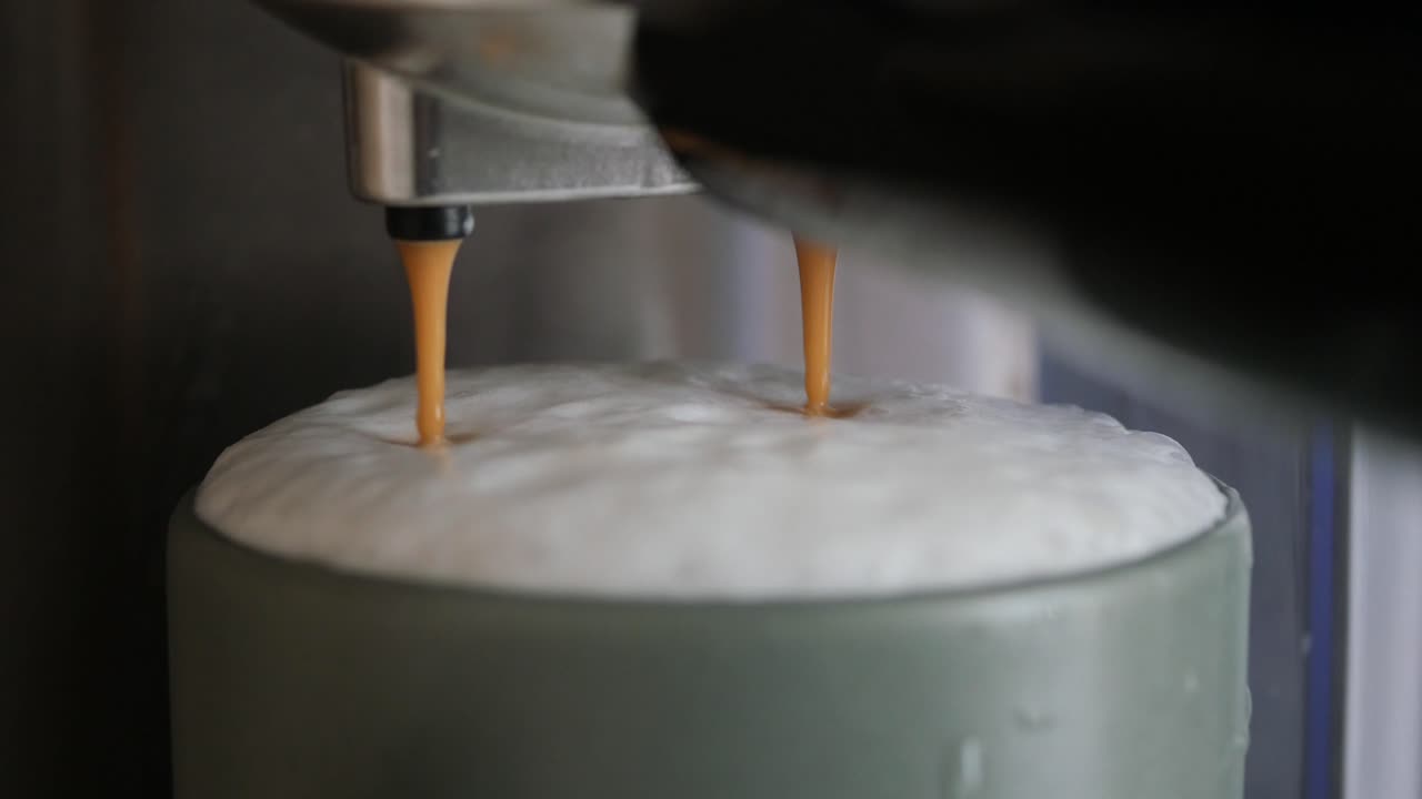 Coffee being dispensed into a mug with frothed milk from an espresso machine