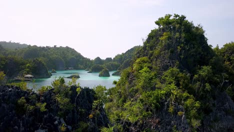 Blue-arrival-pier-on-the-lagoon-of-Piaynemo-islands-in-Raja-Ampat-Indonesia,-Aerial-flyover-shot