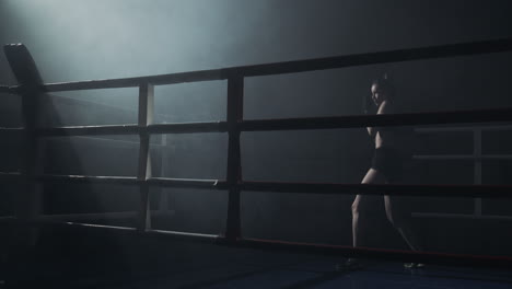 female boxer training in a smoky ring