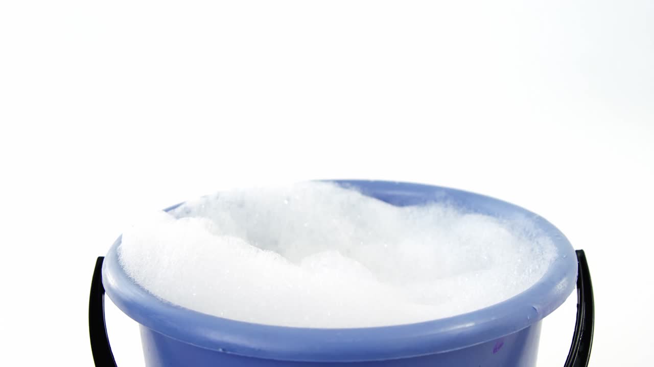 esponja de limpieza cayendo en un cubo de espuma de jabón