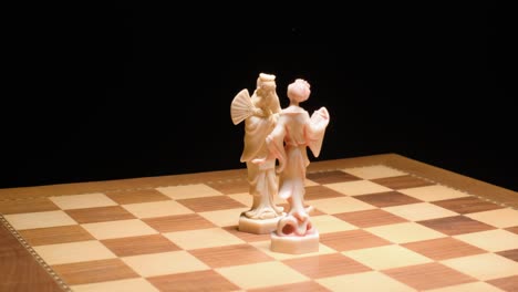 tracking motion king and queen ivory pieces on chessboard, black background