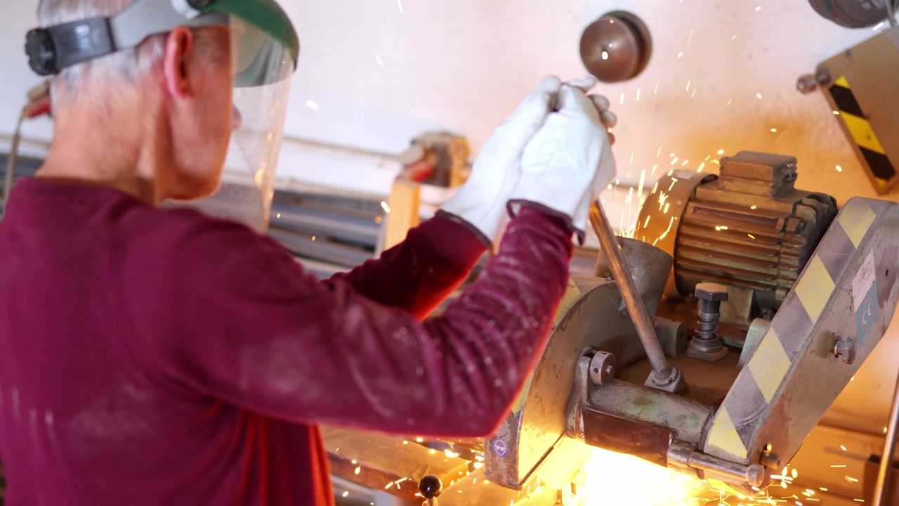 Operaio che taglia un tubo metallico con una smerigliatrice