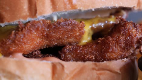 close up of a crispy fried chicken burger with yellow mustard