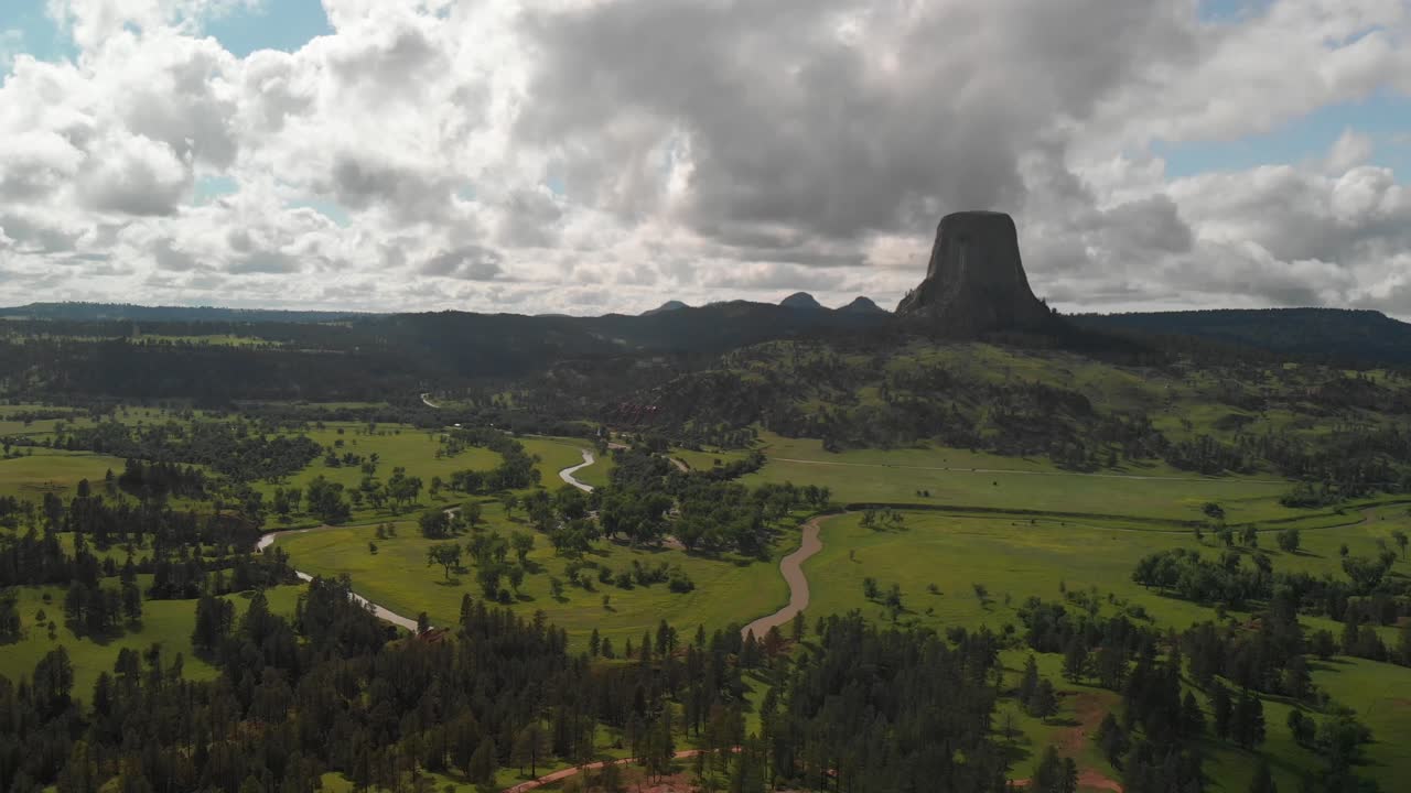 View of beautiful Devils tower and cloudy weather. Aerial flying towards Devils Tower National Monument  pine forest, Wyoming, USA.