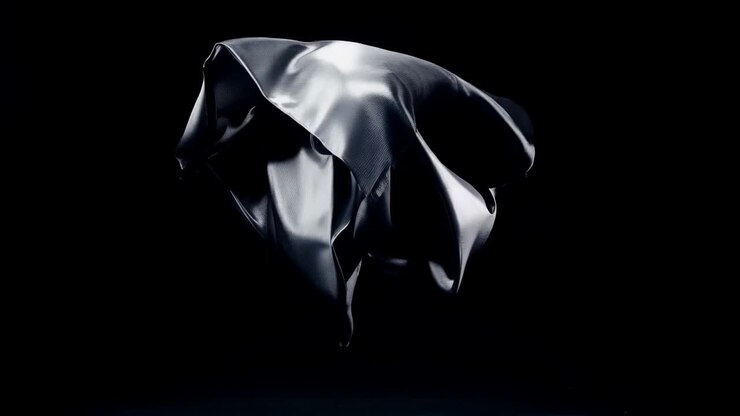 After release descending metallic sheet unfurling crumpling and rotating in studio spotlights