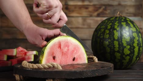 male hand with knife cut half of the watermelon to pieces.