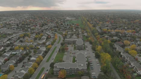 rising aerial footage going straight towards a large sunset over a twisting road with school buses and vehicles parked on it