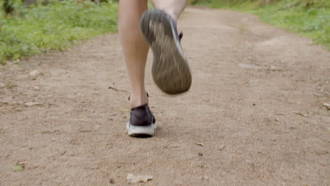 man in sport shoes running on trail in forest