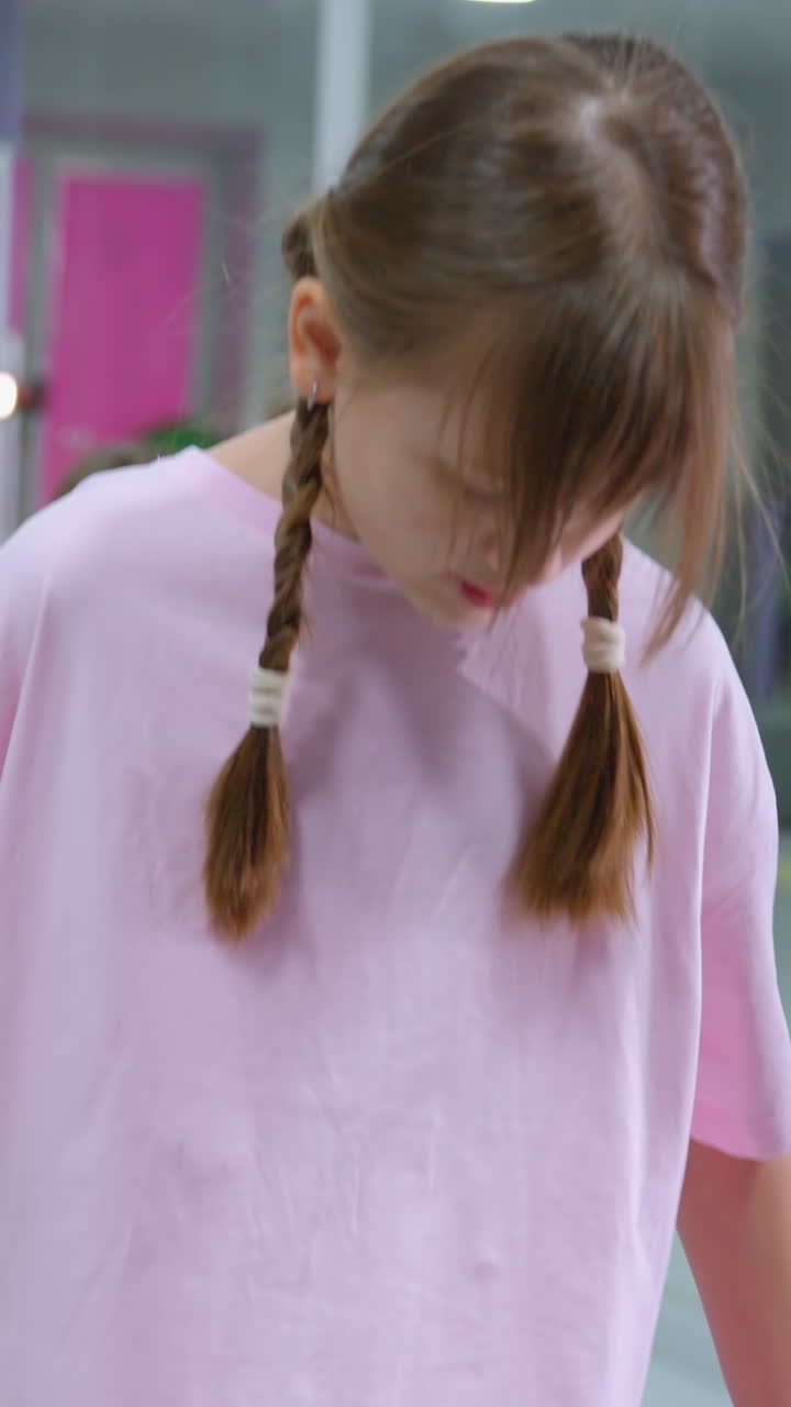 primer plano de un niño pequeño de color rosa equilibrando en una tabla, colocando una pelota de hierro en su lugar, rodeado de otros niños involucrados en actividades de fitness en un gimnasio