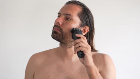 a man is using electric shaver to trim mustache and beard while standing in front of mirror in bathroom at home, shave