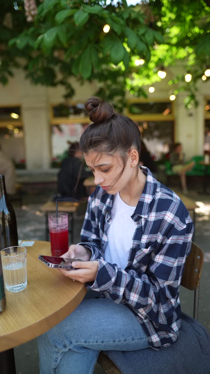 joven usando el teléfono en un café al aire libre
